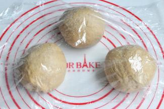 将面团取出，按揉排气后面团均分成三团，盖上保鲜膜松弛15分钟。