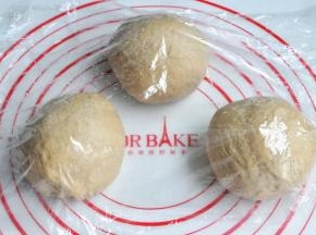 将面团取出，按揉排气后面团均分成三团，盖上保鲜膜松弛15分钟。