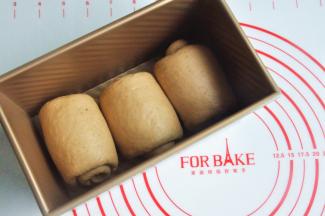 再次擀开成长条状，面团卷起，收口朝下放置，将面团放入吐司模。