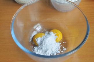 在装有蛋黄的打蛋盆中倒入糖粉。