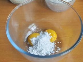 在装有蛋黄的打蛋盆中倒入糖粉。