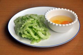 准备材料，苦瓜切成2半，将中间的瓤去掉，然后将苦瓜内层的白色膜刮除干净，减少苦瓜的苦涩感，斜切薄片。