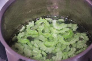 在小锅中烧开水，放1勺盐和玉米油，将苦瓜片放入锅中焯至变色即可捞出沥干水份冷却备用。