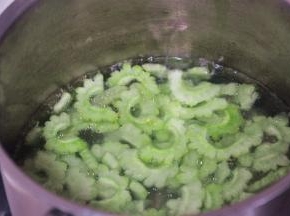 在小锅中烧开水，放1勺盐和玉米油，将苦瓜片放入锅中焯至变色即可捞出沥干水份冷却备用。