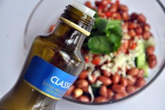 倒入适量橄榄油，也可以用锅里炸花生米剩下的油，然后拌均匀即可。