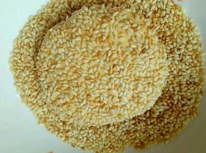包好的南瓜饼放入熟芝麻的容器里，沾满芝麻，依次做完。