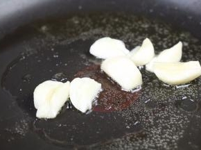 不粘锅中倒入适量的食用油，放入大蒜，小火煸炒出香味。
