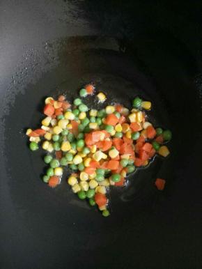 倒入比平时烧菜多一点的油加热，加入玉米青豆胡萝卜丁翻炒断生