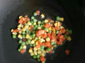 倒入比平时烧菜多一点的油加热，加入玉米青豆胡萝卜丁翻炒断生