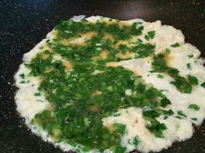 锅里稍微放一点点油，倒2大勺韭菜蛋液，摊均匀，