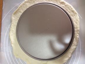 披萨盘倒扣在面团上用刀切成与披萨盘大小一样的圆面团