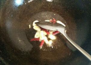 锅内放适量油 油烧热冒烟后 放入大蒜和干辣椒  花椒煸炒出香味