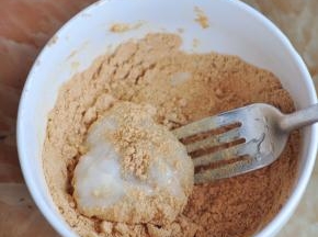 用勺子舀起一块糯米团，放入黄豆粉中。