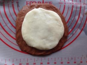 将可可面团和麻薯团擀成圆形，麻薯团擀得比可可面团小一点，放在可可面团上面