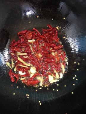 锅洗净重新烧热倒入适量的油，放入生姜，蒜瓣，花椒小火慢慢的爆出香味后，倒入干红辣椒继续小火慢慢的炸出红油来！

