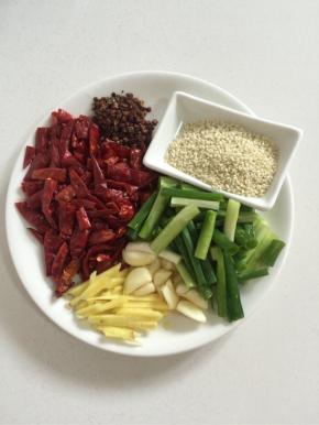 腌制鸡块的时候我们来准备做辣子所需的配料： 干红辣椒用简单剪成2cm左右长的段儿，蒜瓣剥皮按压一下，生姜削皮切成丝，葱切成段，准备好熟芝麻，花椒！

