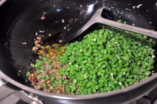 倒入焯过水的豇豆，翻炒均匀。