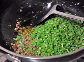 倒入焯过水的豇豆，翻炒均匀。