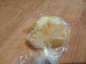 拿一个煮熟的土豆放进保鲜袋，袋口转一圈，用刀背拍一下，这样拍好的土豆饼不会散。