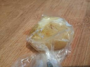 拿一个煮熟的土豆放进保鲜袋，袋口转一圈，用刀背拍一下，这样拍好的土豆饼不会散。