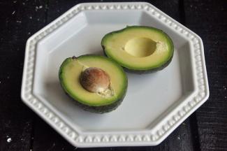 将牛油果对半切开，牛油果外皮深的成熟的。