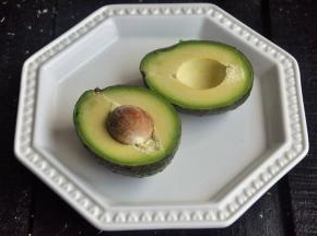 将牛油果对半切开，牛油果外皮深的成熟的。