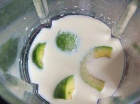 将果肉对切一刀，放入破壁机中，倒入牛奶和白砂糖。