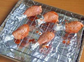 将鸡腿摆在烤网上并用刷子刷上一层腌料，烤盘铺锡纸，烤的时候会有油汁滴落。如果直接滴在烤盘上，烤完烤盘很难清理。