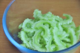 苦瓜切成2半，将中间的瓤去掉，然后将苦瓜内层的白色膜刮除干净，减少苦瓜的苦涩感，斜切薄片。