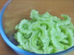 苦瓜切成2半，将中间的瓤去掉，然后将苦瓜内层的白色膜刮除干净，减少苦瓜的苦涩感，斜切薄片。