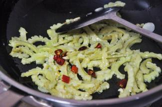 等苦瓜起皱时，倒入干辣椒，继续煸炒。