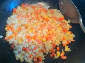 然后放入胡萝卜丁  玉米粒  火腿肠炒匀   加入鸡精撒上葱花即可~够速度吧~