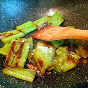 用锅铲轻轻按压青椒，并不时翻面，使之均匀受热，两面表皮都煸出皱纹，