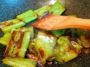 用锅铲轻轻按压青椒，并不时翻面，使之均匀受热，两面表皮都煸出皱纹，
