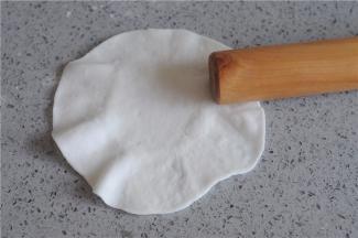 取一个小剂子，稍微沾点粉，用擀面杖擀成圆形，用力将四周压薄，变成四周薄中间厚的圆片，再用擀面杖的一头沿着面片的周围用力擀压，让周围变的更薄，成木耳状