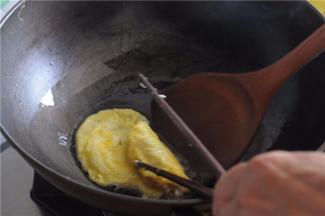 用勺子和筷子相互合作，将鸡蛋饼把肉馅包裹起来