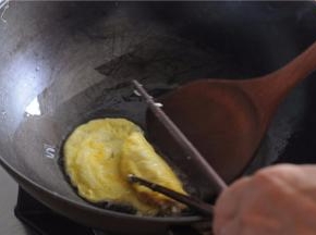用勺子和筷子相互合作，将鸡蛋饼把肉馅包裹起来