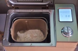 把液体材料放入面包桶中，面粉铺在上面，对角分别上放上盐、糖、奶粉，在面粉中间挖一个小坑，放上酵母，启动面包机揉面程序10分钟。