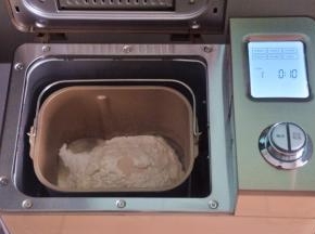 把液体材料放入面包桶中，面粉铺在上面，对角分别上放上盐、糖、奶粉，在面粉中间挖一个小坑，放上酵母，启动面包机揉面程序10分钟。