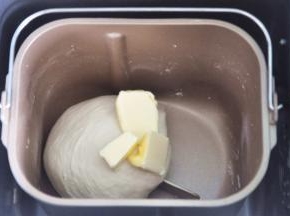 揉至面筋扩展，表面光滑，加入软化的黄油。