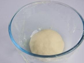 将揉好的面团放入烤箱中进行第一次发酵，在面团上盖一层保鲜膜，烤箱里放一碗温水，30度1小时。