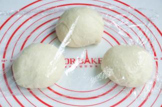 将面团取出，按揉排气后面团均分成三团，盖上保鲜膜松弛15分钟。