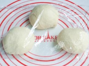 将面团取出，按揉排气后面团均分成三团，盖上保鲜膜松弛15分钟。