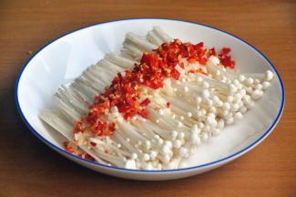 将小米椒和蒜剁碎铺在金针菇上面，辣椒根据个人喜好放。