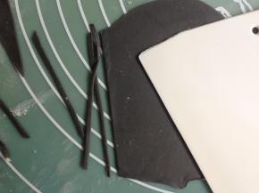 黑色小面团同样擀平擀簿，切成更细的长条，再切成小段，用来做猫须