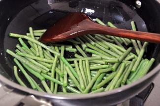 用剩余的油，倒入豇豆，炸至表皮起皱，豆角一定要炒熟，以防中毒。