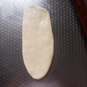 取一个松弛好的面团，从中间上下的顺序擀薄。有气泡的话用手拍掉。