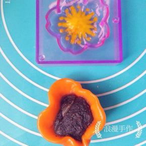 胡萝卜粉团取25克包入一个豆沙馅儿，慢慢收紧口，放入刚刚填满花纹的阳晨和果子模具中。