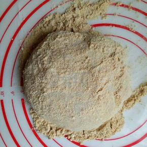 炒好的黄豆粉放在面板上，把蒸好的糯米团放上去，如图，用擀面杖擀长。