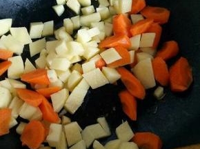 锅中加入适量油，油温7成时加入切好的土豆煸炒，再加入胡萝卜。